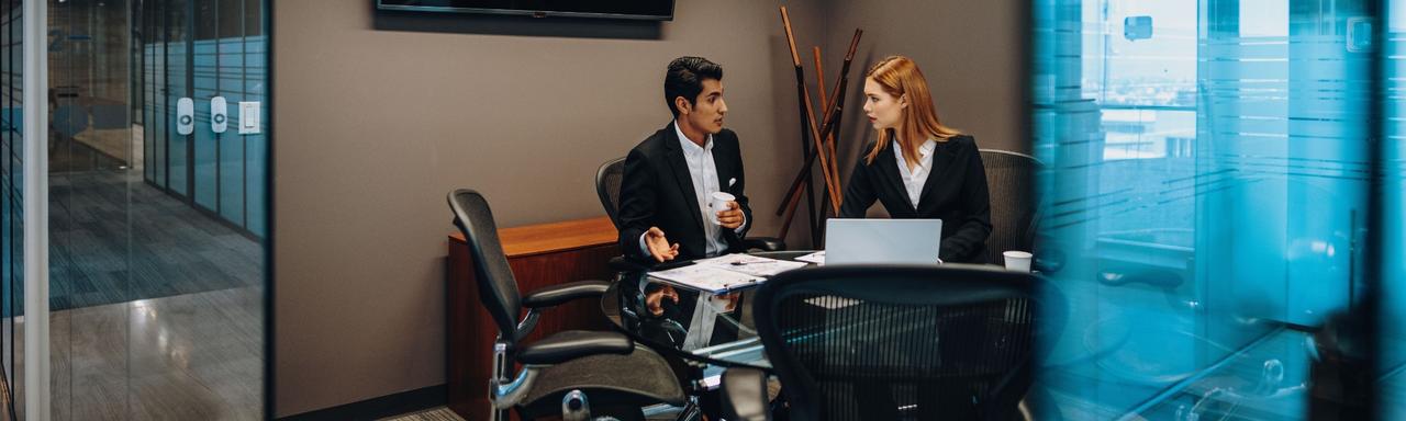 Two people in conference room working on computer
